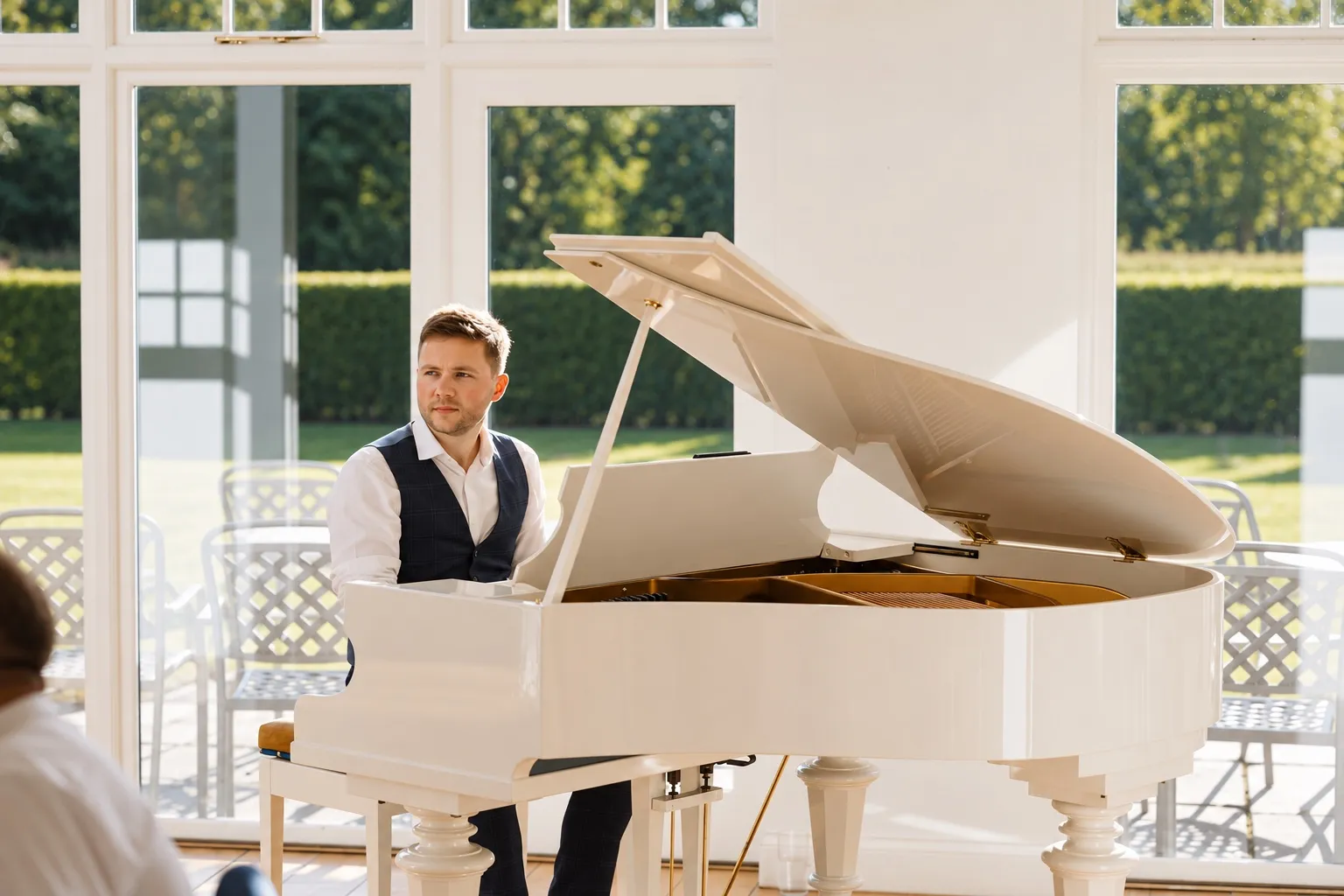 Finn at a white grand piano in a sunlit orangery at Hackness Grange
