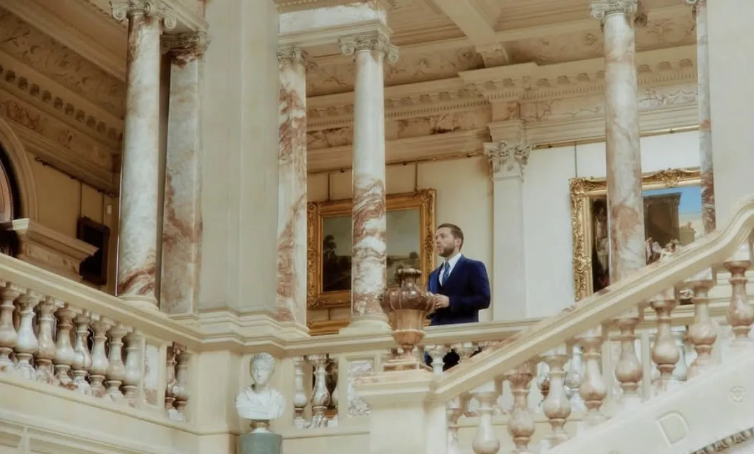 Finn in a suit on a grand marble staircase