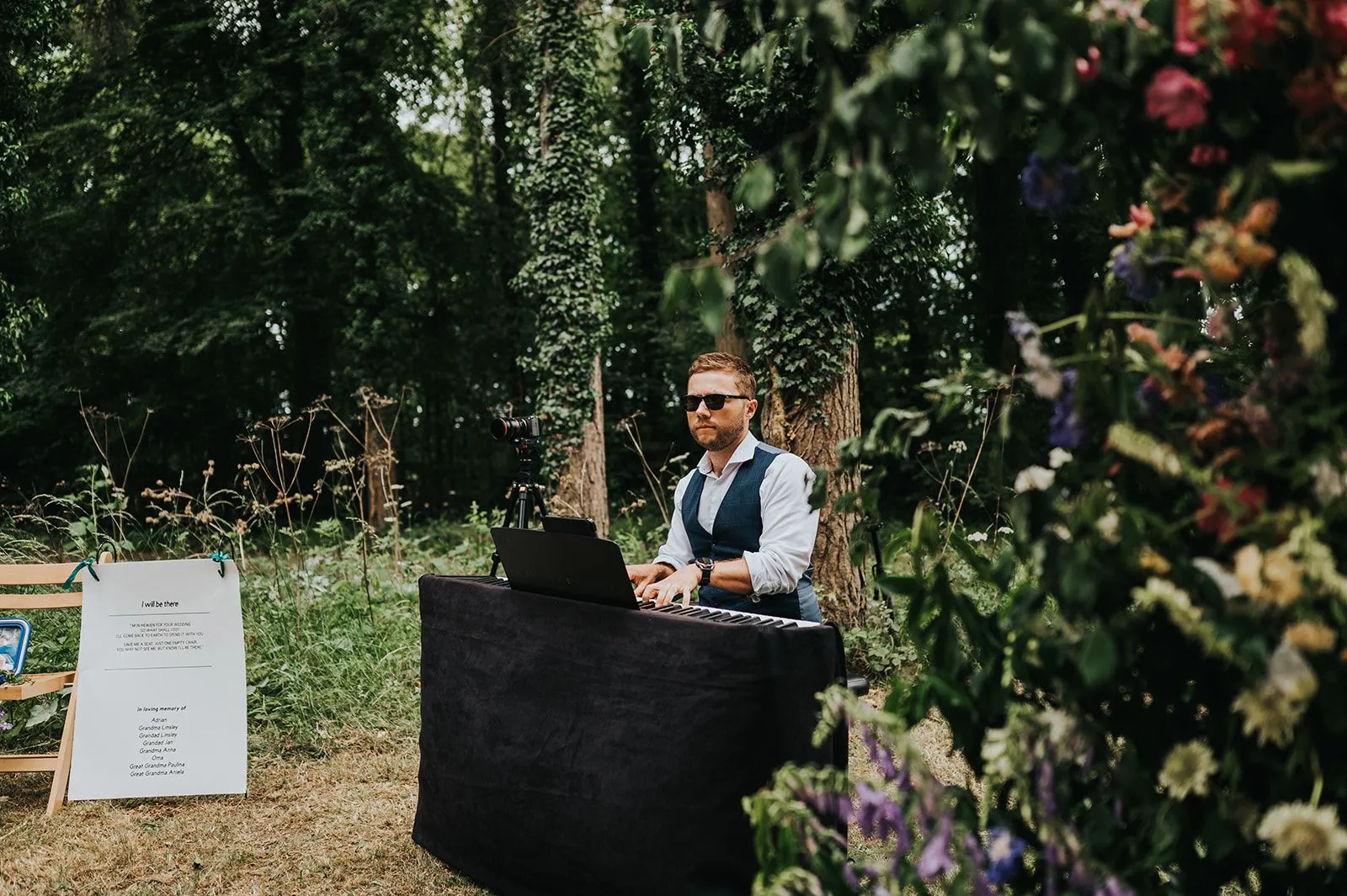Finn playing a keyboard in a woodland clearing, framed by wild flowers